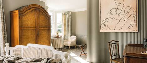 A bedroom with a bed, a wooden wardrobe, a dining table, and a chair.