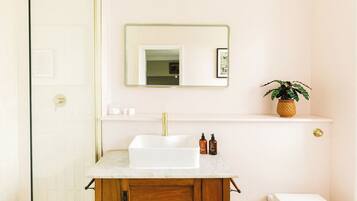 A bathroom with a white sink, wooden cabinet, and a mirror above it.