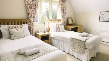 A bedroom with two beds, a wooden headboard, a nightstand with a lamp, and a framed picture on the wall.