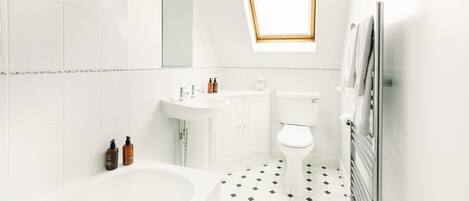 Une salle de bain moderne avec une baignoire sur pieds, des toilettes, un lavabo et un miroir.