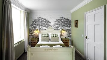 A bedroom with a large bed, two nightstands, a dresser, and a door.