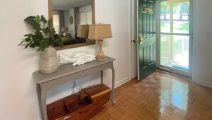 A room with a wooden floor, a console table with a lamp, a mirror, and a plant. - Waterfront cabin on Lake Martin near restaurants, golf and, AU football (Dadeville)