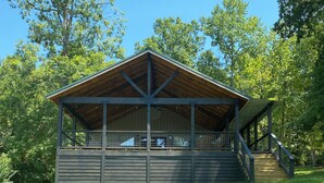 A wooden pavilion with a covered deck and stairs leading up to it, surrounded by lush green grass and trees. - Waterfront cabin on Lake Martin near restaurants, golf and, AU football (Dadeville)