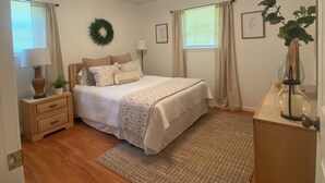 A bedroom with a bed, nightstand, lamp, and a small table with a plant. - Waterfront cabin on Lake Martin near restaurants, golf and, AU football (Dadeville)