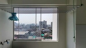 A room with a window overlooking a cityscape, a metal rack, and a water tap.
