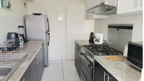 A modern kitchen with a gas stove, a coffee maker, and a refrigerator.