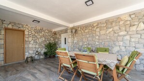 A dining area with a stone wall, a wooden door, and a table with chairs.
