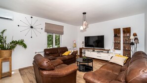 A modern living room with leather sofas, a flat-screen TV, and a wooden coffee table.