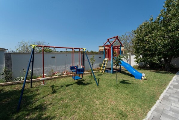 Un parque infantil con columpios, un tobogán y una estructura para escalar.