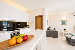 A modern kitchen with white cabinets, a wooden countertop, and a fruit bowl.