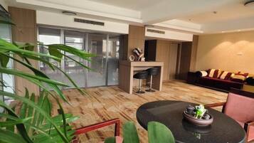 Habitación de hotel moderna con zona de comedor, un conjunto de sofás y un amplio ventanal con vistas.