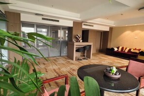A modern hotel room with a dining area, a sofa set, and a large window with a view. - Great Wall Hotel (Shaoyang)