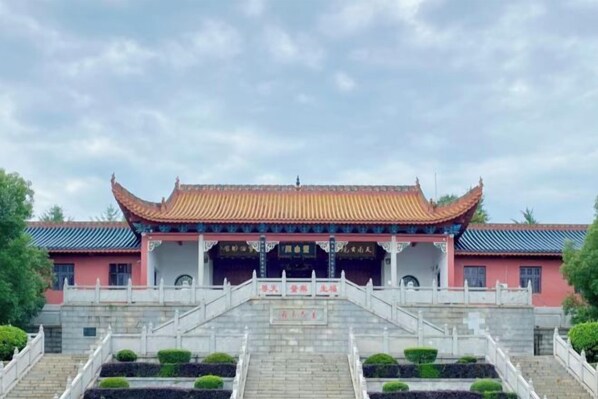 A traditional building with a symmetrical facade, a central entrance, and a staircase leading up to it.