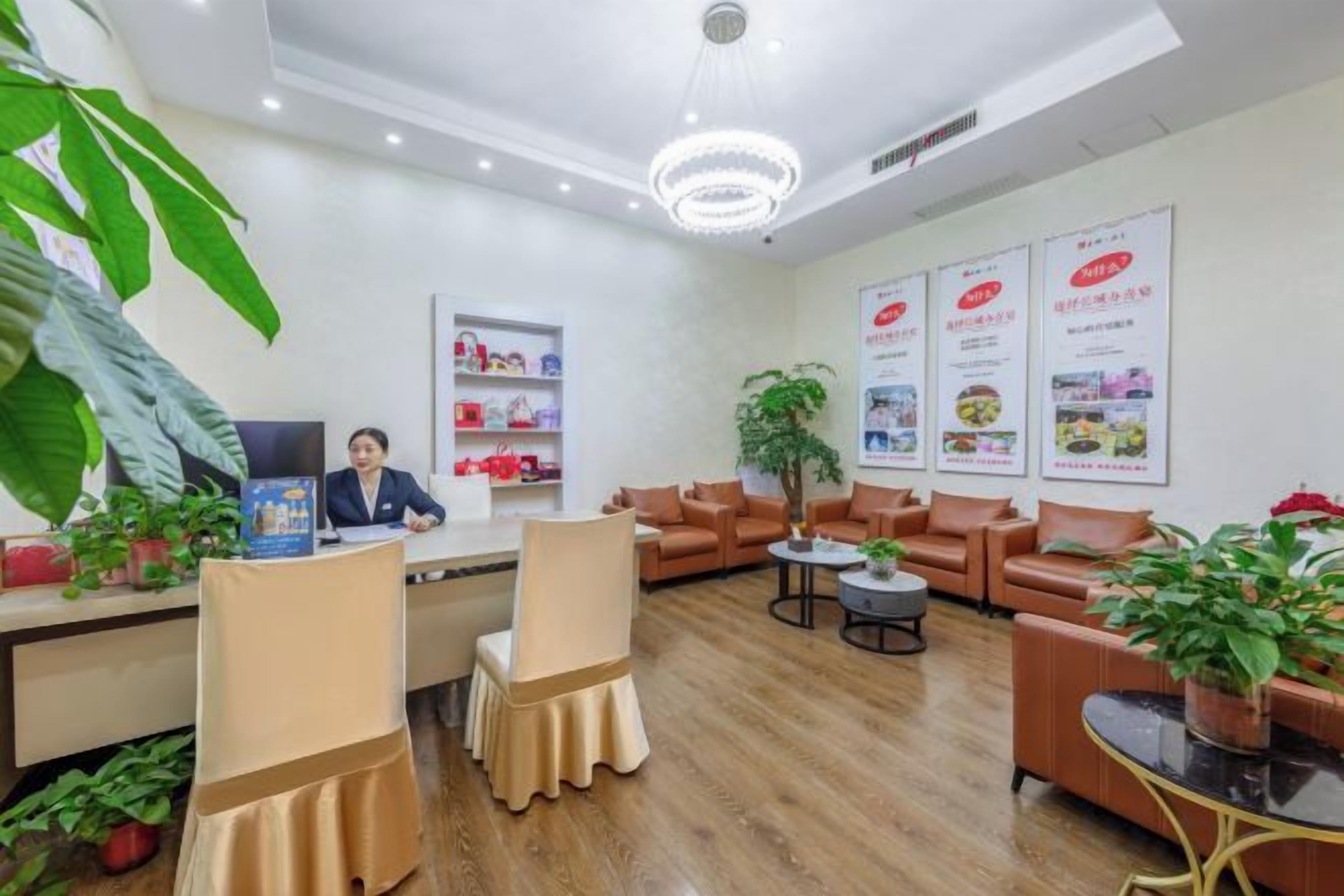 A reception area with a desk, chairs, a large plant, and a chandelier.