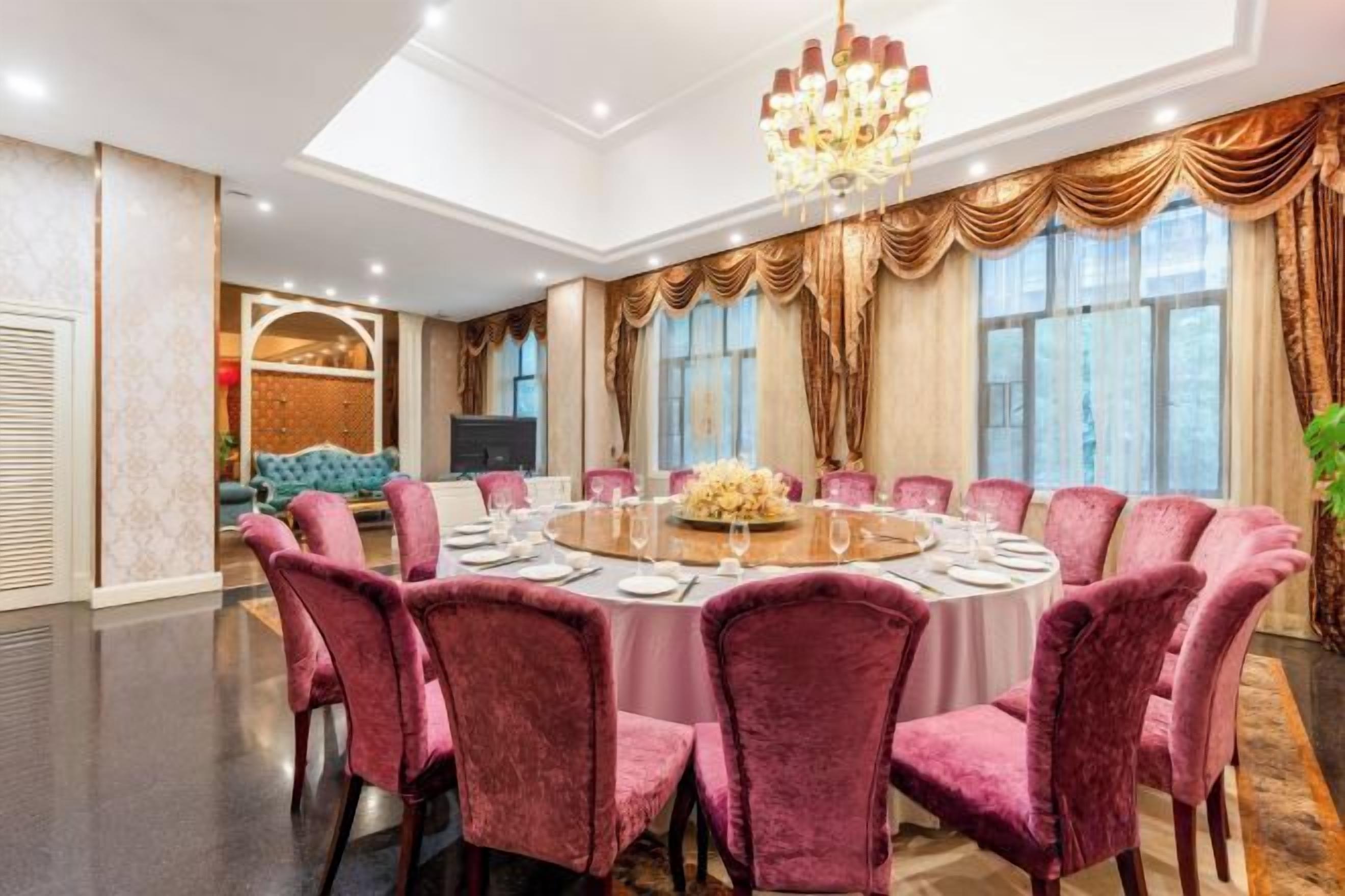 Un comedor formal con una mesa redonda, varias sillas y una araña.