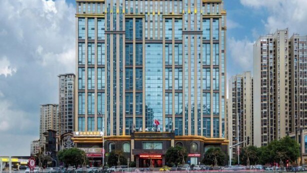 Un edificio de gran altura con un diseño arquitectónico moderno, que presenta una entrada destacada con un toldo rojo e izado una bandera.
