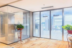 Un interior moderno con separadores de vidrio, una planta en maceta y vistas al exterior.