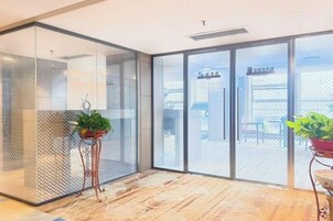 Un interior moderno con separadores de vidrio, una planta en maceta y vistas al exterior.
