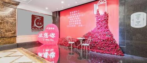 Un hall d’hôtel doté d’un sol réfléchissant, d’un mur rouge orné d’un élément décoratif et d’une enseigne avec du texte.