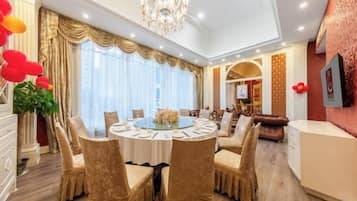 A dining area with a round table, chairs, and a chandelier.