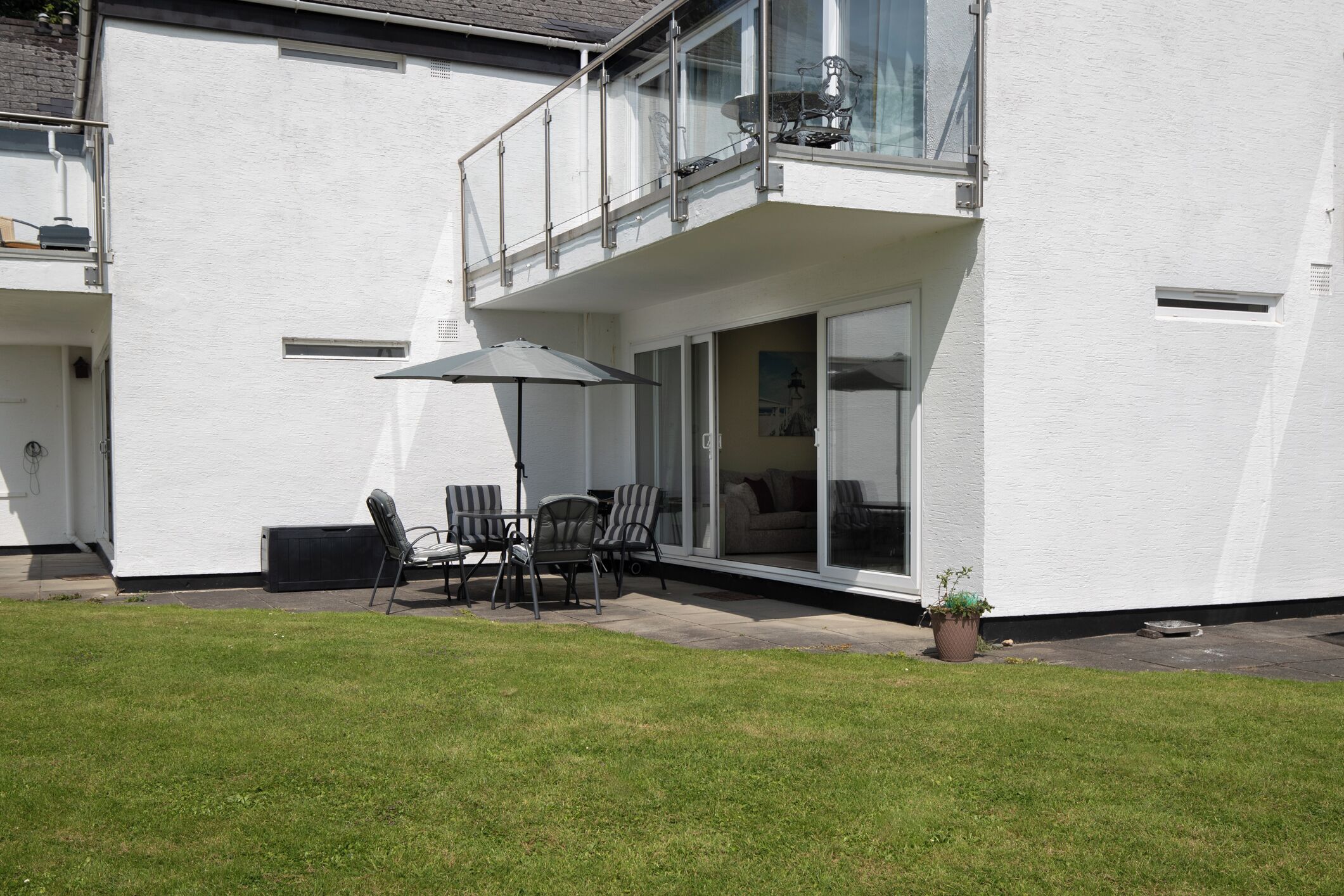 Un bâtiment blanc doté d’un balcon, d’une terrasse et d’une plante en pot.