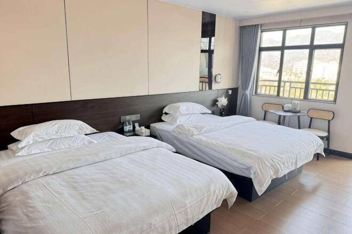 Ein Hotelzimmer mit zwei Betten, einem kleinen Tisch, einem Stuhl und einem Fenster mit Blick.