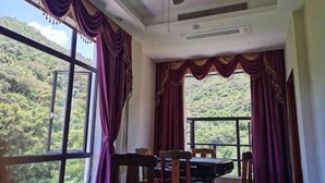 A room with large windows, a ceiling fan, and a table with chairs.