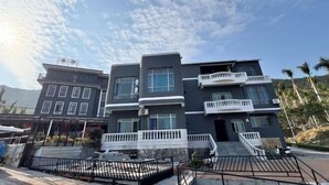 A multi-story building with balconies, a staircase, and a gated entrance.