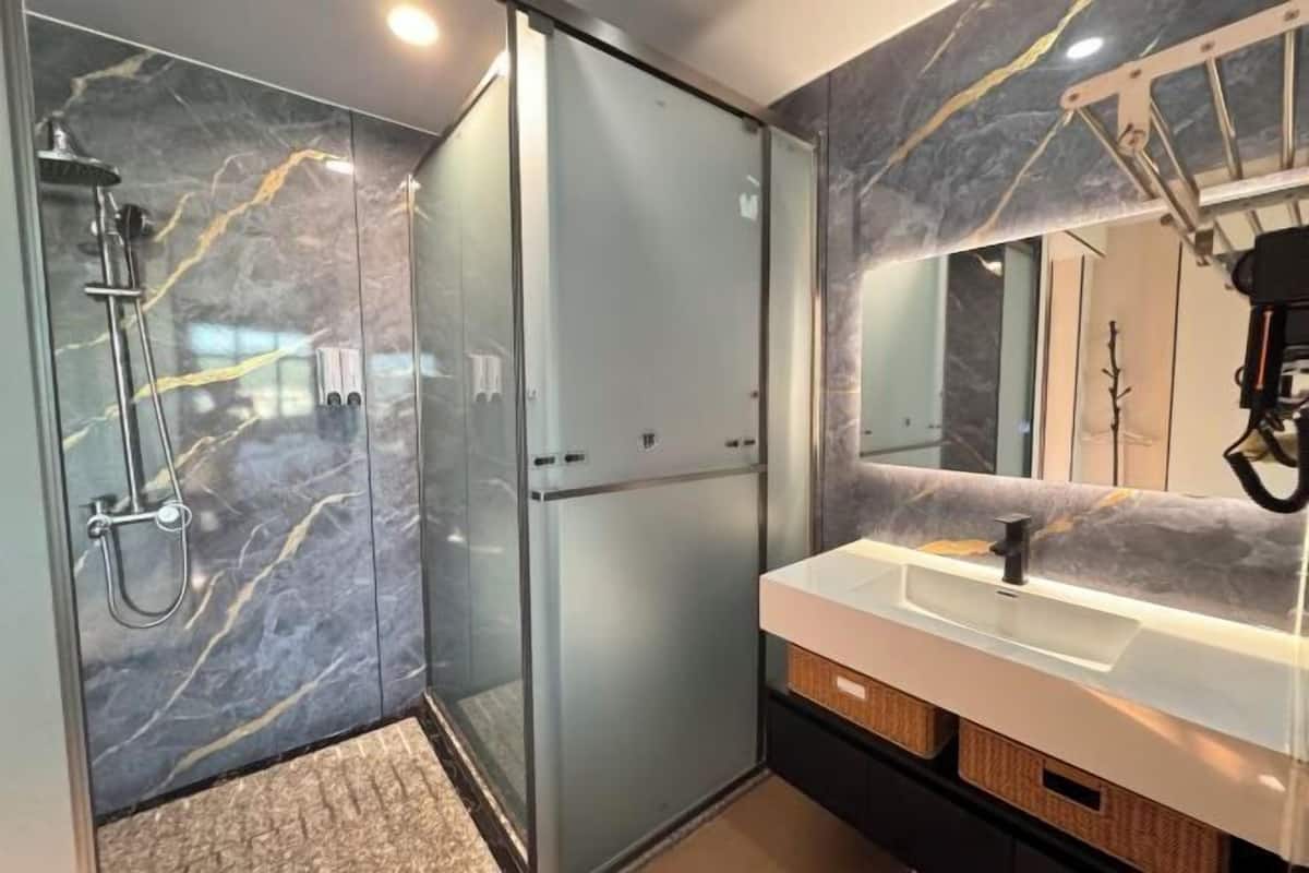 Ein modernes Badezimmer mit einer in Glas eingefassten Dusche, einem weißen Waschbecken und einer Marmor-Spritzschutzwand.