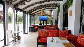 Un grand espace intérieur comprenant une longue table, des canapés rouges à motifs et un téléviseur.