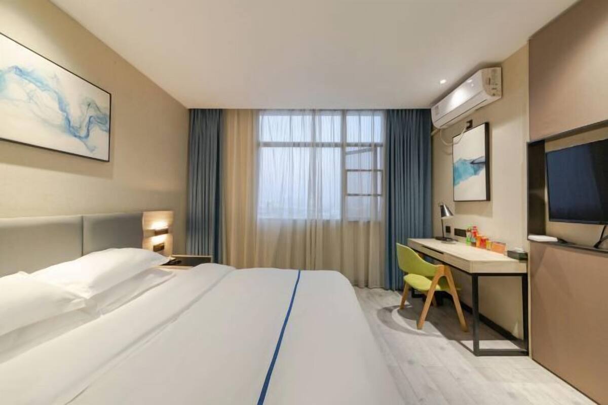 Une chambre d’hôtel équipée d’un lit, d’un bureau, d’une chaise et d’œuvres d’art accrochées aux murs.
