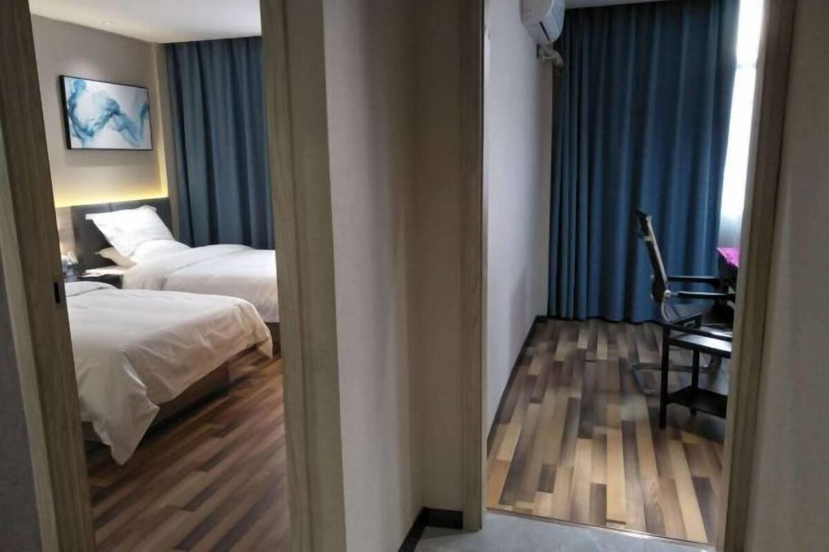 Une chambre d’hôtel avec deux lits, un bureau et une chaise.
