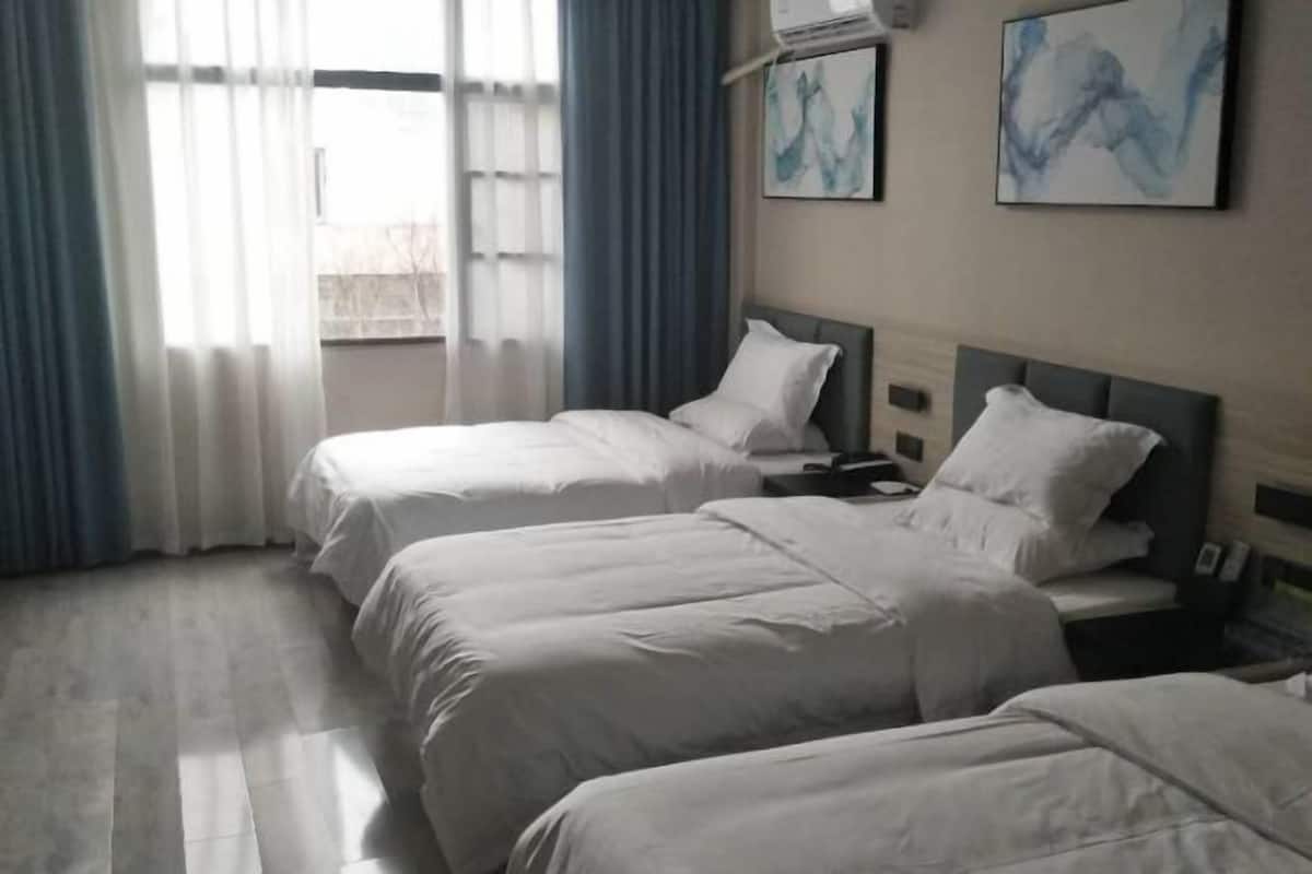 Une chambre d’hôtel avec deux lits, une table de chevet avec une lampe et une fenêtre avec des rideaux.
