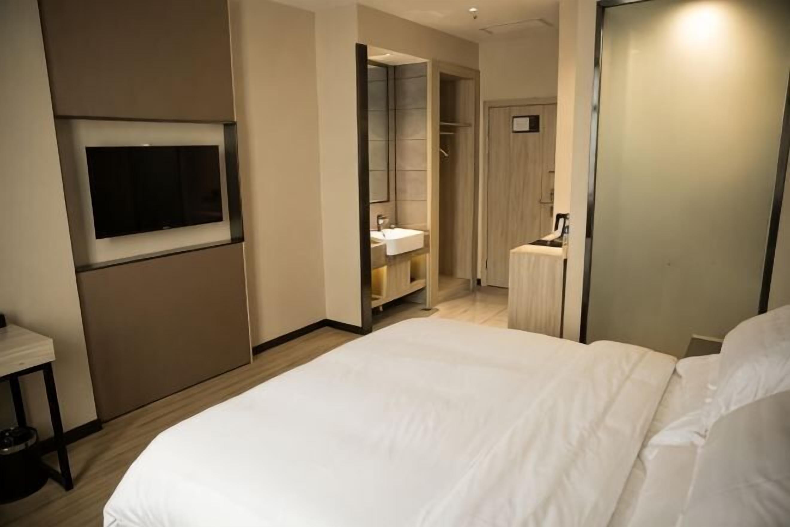 Een hotelkamer met een bed, een televisie, een badkamer met een wastafel en een kledingkast.