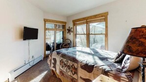 A bedroom with a bed, a television, and a window with a view of trees. - Tenderfoot Lodge 2 Bedroom at the Mountain House Base (Keystone)