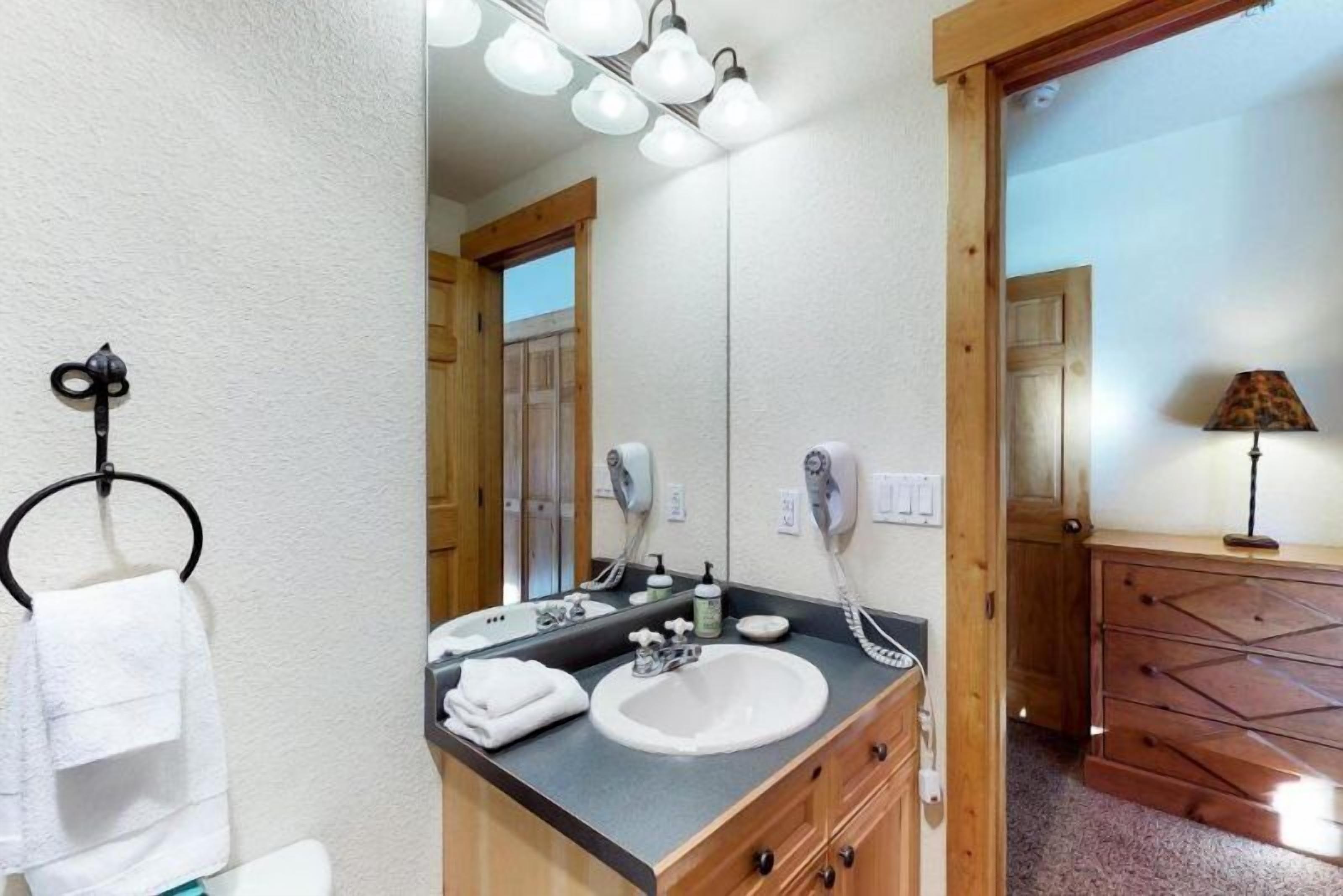 A bathroom with a sink, mirror, towel rack, and a wooden cabinet.