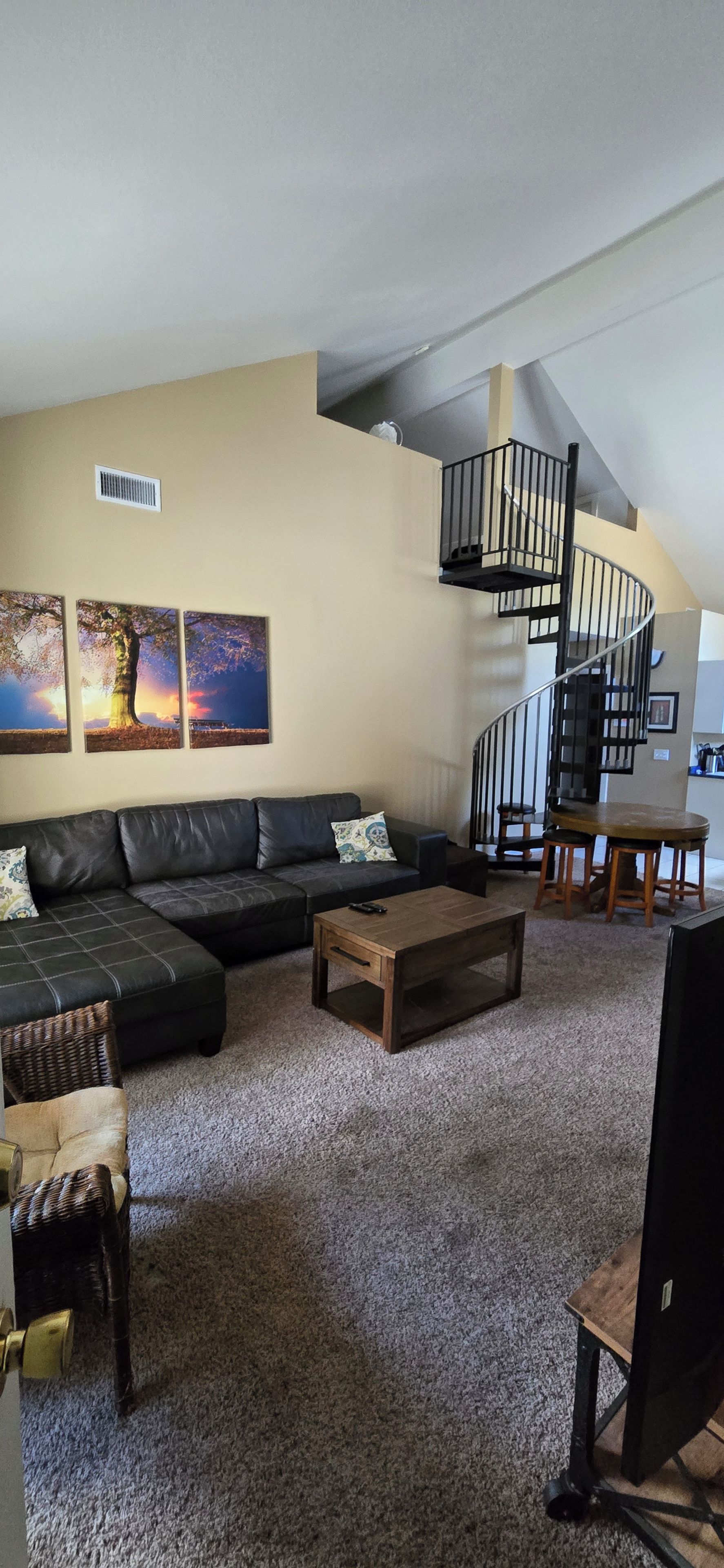A living room with a sectional sofa, a coffee table, and a staircase leading to an upper level.