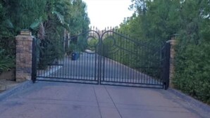 A gated entrance with a metal gate, stone pillars, and a paved driveway. - Very Private Guest House for 6 on Private 3.25 acre Estate behind 2 secure gates (Simi Valley)