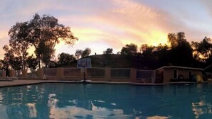 A swimming pool with a sunset in the background, surrounded by trees and a fence. - Very Private Guest House for 6 on Private 3.25 acre Estate behind 2 secure gates (Simi Valley)