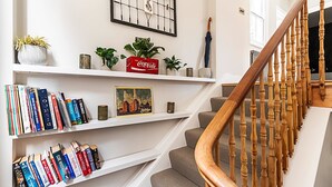 A staircase with wooden balusters and a white wall with shelves holding books and decorative items.