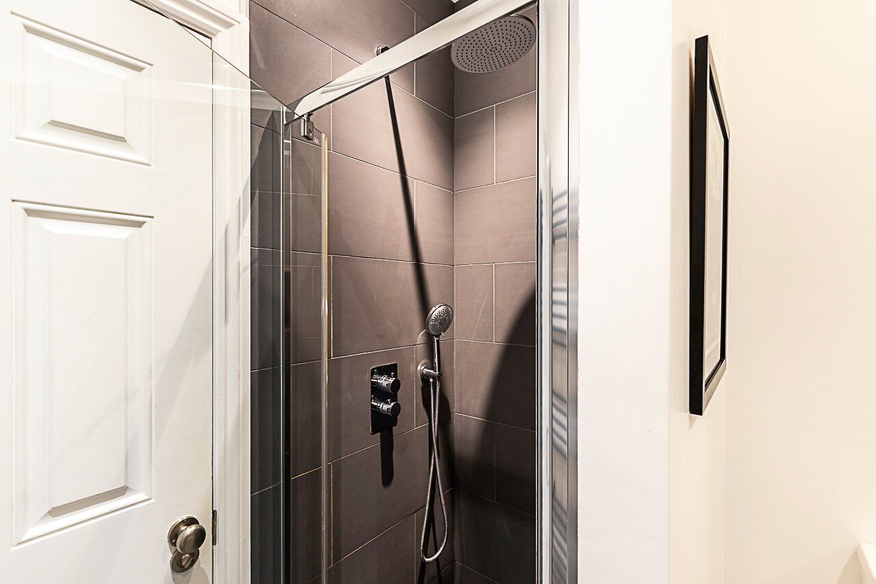 A modern shower with a handheld showerhead and a wall-mounted faucet.