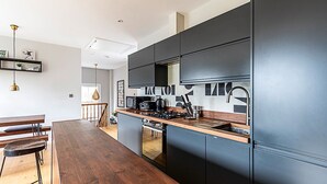 A modern kitchen with dark cabinetry, a wooden countertop, and a built-in dishwasher.
