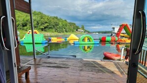 A wooden deck with inflatable water toys and a boat docked in the background. - Banrai WanWan Resort (Si Sawat)