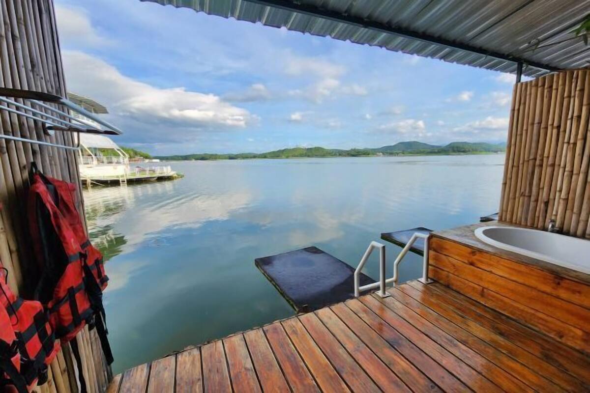 A wooden deck with a view of calm water and distant hills.