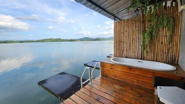 A wooden deck with a built-in bathtub and a small seating area overlooking a calm lake. - Banrai WanWan Resort (Si Sawat)