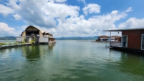 A lakeside hotel with floating structures, a dock, and a clear view of the surrounding landscape. - Banrai WanWan Resort (Si Sawat)
