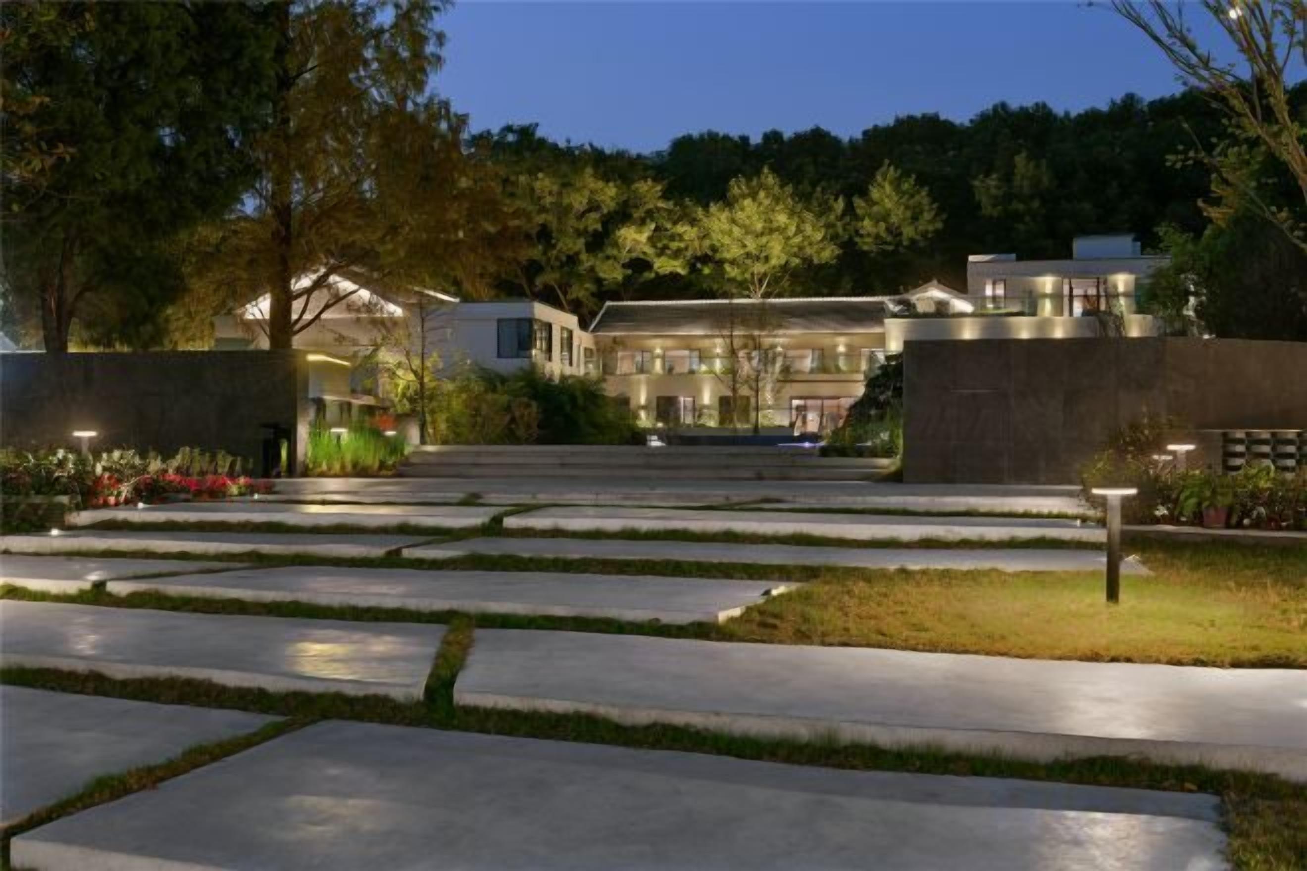 A landscaped courtyard with a paved walkway leading to a building with multiple windows.