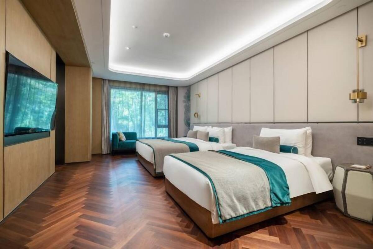 Ein modernes Hotelzimmer mit zwei Betten, einem großen Fenster und Holzboden.
