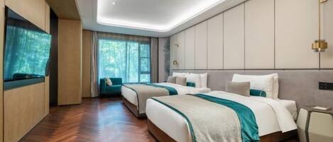 A modern hotel room with two beds, a large window, and a wooden floor.