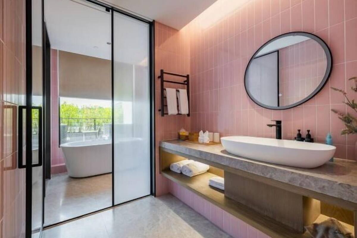 Ein modernes Badezimmer mit freistehender Badewanne, einem runden Spiegel und einem Waschtisch mit großem Becken.